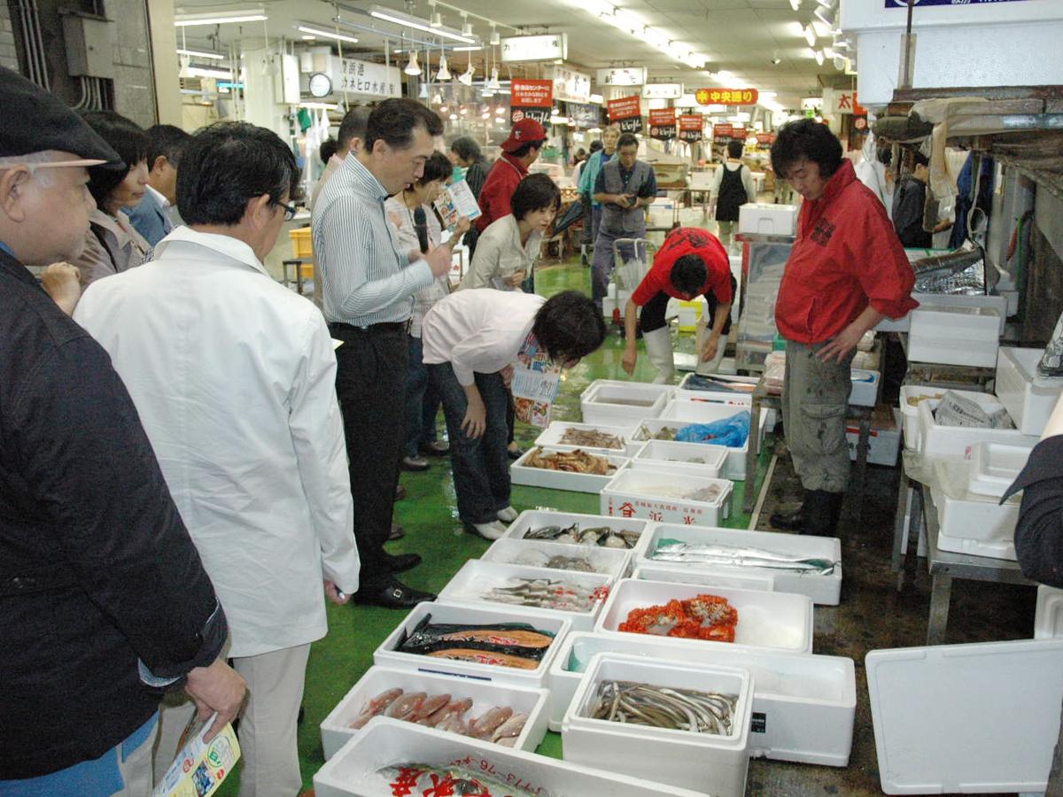 並んだ沢山の魚介類を眺める人達